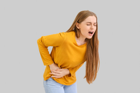 Young woman with appendicitis on gray backgroundの写真素材