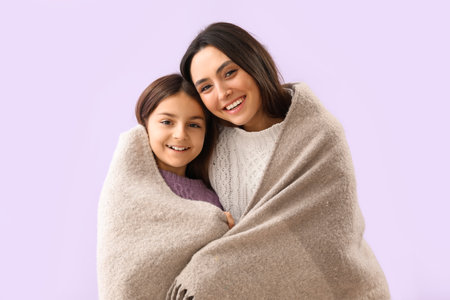 Little girl and her mother with warm plaid on lilac backgroundの写真素材