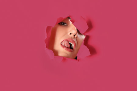 Young woman visible through hole in pink paper