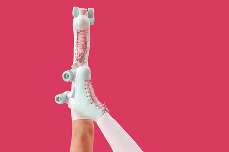 Legs of young woman in roller skates on pink background