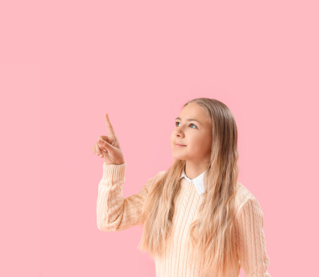 Little girl using virtual screen on pink backgroundの写真素材