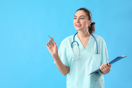 Female medical assistant with clipboard on light blue backgroundの写真素材