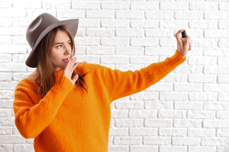 Young woman with pepper spray for self-defence on white brick backgroundの写真素材