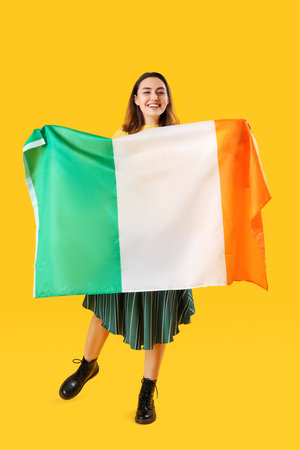 Young woman with flag of Ireland on yellow backgroundの写真素材