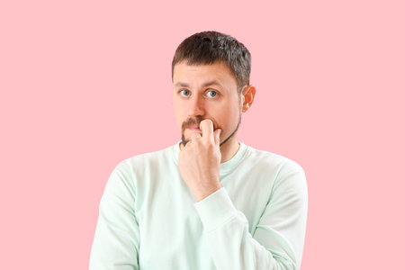 Handsome man biting nails on pink background, closeupの写真素材