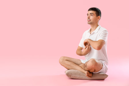 Young man meditating on pink backgroundの写真素材