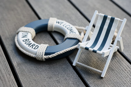 Toy sun lounger and ring buoy on gray wooden background