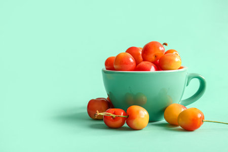 Cup with sweet yellow cherry on turquoise backgroundの写真素材