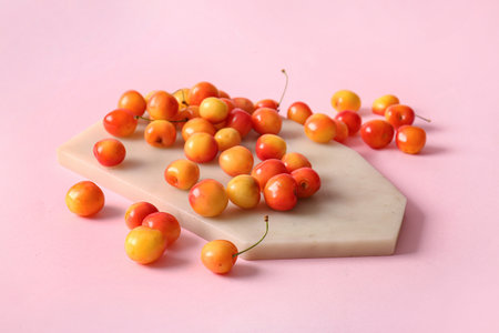 Board with sweet yellow cherry on pink backgroundの写真素材
