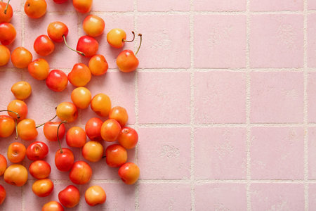 Many sweet yellow cherries on pink tile backgroundの写真素材
