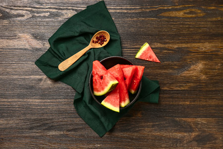 Bowl with pieces of fresh watermelon and seeds on wooden backgroundの写真素材