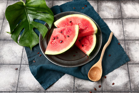 Plate with pieces of fresh watermelon and seeds on gray tile backgroundの写真素材