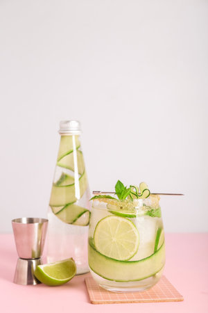 Glass of cucumber mojito with jigger on pink backgroundの写真素材