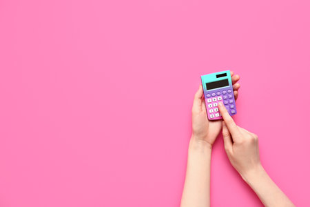Woman using calculator on pink backgroundの写真素材