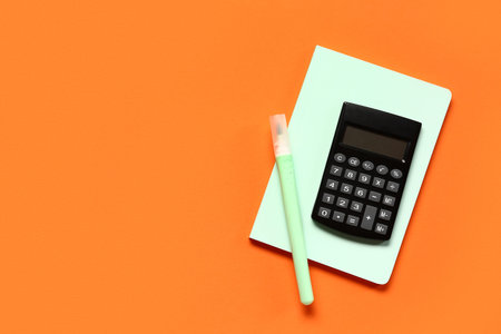 Modern calculator with stationery on orange background