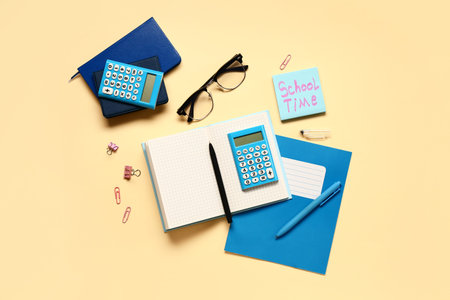 Sticky note with text SCHOOL TIME, stationery and calculator on pale yellow background
