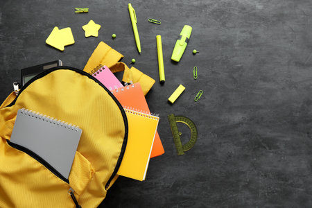 Yellow school backpack with notebooks and stationery on black backgroundの写真素材