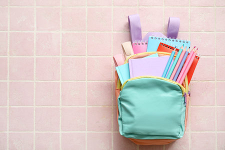 Colorful school backpack with notebooks, pencils and markers on pink tile backgroundの写真素材