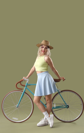 Young woman in summer hat with bicycle on green backgroundの写真素材