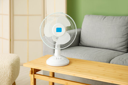 Wooden table with modern electric fan in interior of living roomの写真素材