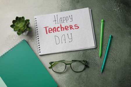 Notebooks with text HAPPY TEACHERS DAY, eyeglasses and houseplant on grunge green gradient backgroundの写真素材