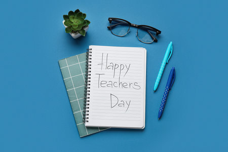 Notebooks with text HAPPY TEACHERS DAY, eyeglasses and houseplant on dark blue backgroundの写真素材
