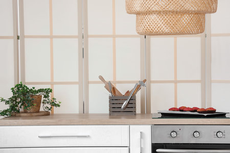 Tray with fresh muffins, utensils and houseplant on wooden kitchen counter