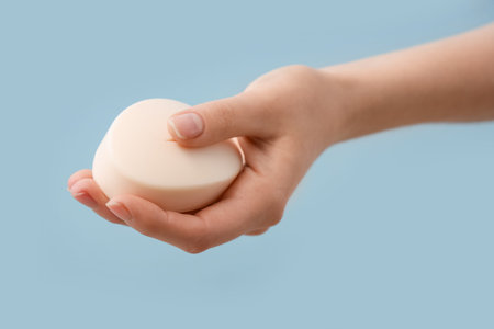 Hand with soap on light blue background
