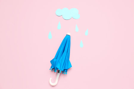 Umbrella with paper cloud and rain drops on pink background. weather forecast conceptの写真素材