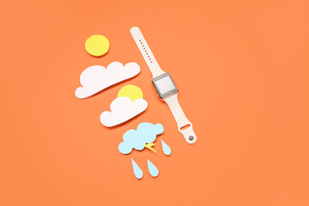 Smartwatch with paper clouds, sun and rain drops on red background. weather forecast conceptの写真素材