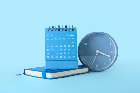 Flip paper calendar for October with notebook and alarm clock on blue backgroundの写真素材