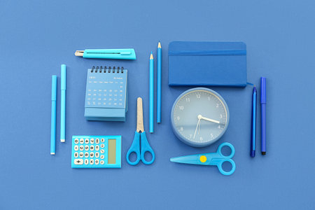 Flip paper calendar with alarm clock and stationery on blue background