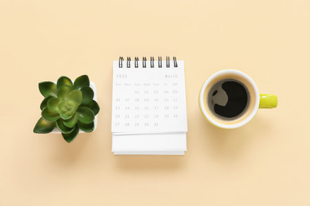 Flip paper calendar for March with cup of coffee and houseplant on beige backgroundの写真素材