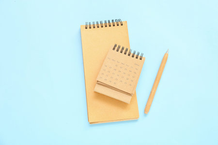 Flip paper calendar for June with notebook and pen on blue background