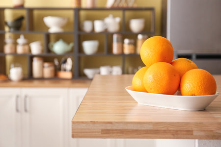 Plate with oranges on table in stylish kitchenの写真素材