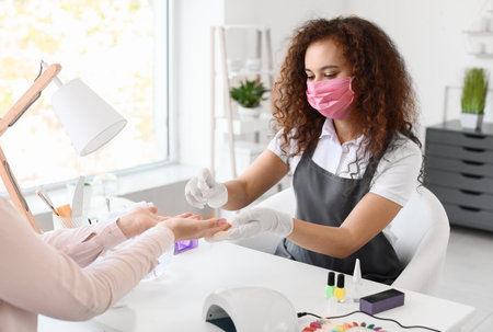 Manicure master working with female client in beauty salonの写真素材