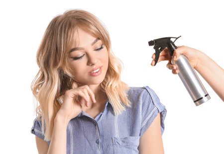 Beautiful young woman and hand with hair spray on white backgroundの写真素材