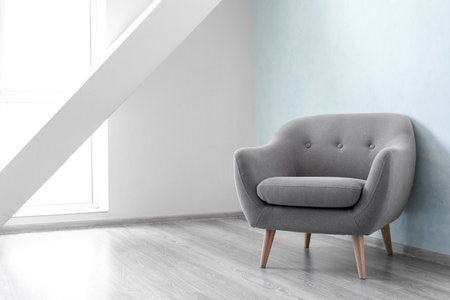Comfortable armchair near light wall in roomの写真素材