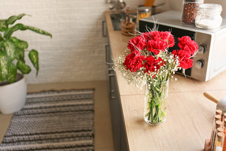 Vase with bouquet of beautiful flowers on table in kitchenの写真素材