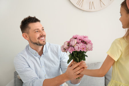 Little daughter giving bouquet of flowers for her father at homeの写真素材