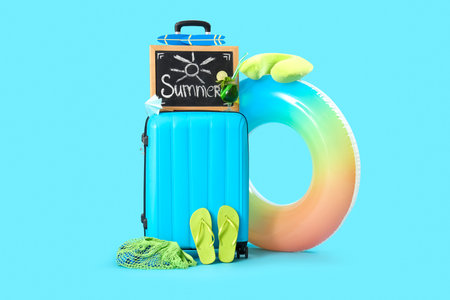 Suitcase, beach accessories and blackboard with word SUMMER on blue background. travel conceptの写真素材