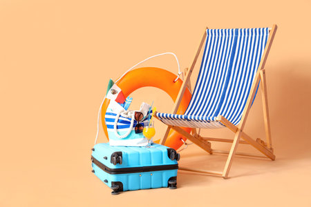 Deckchair with suitcase, ring buoy and beach accessories on beige background. travel concept