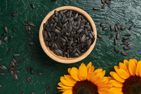Sunflowers and bowl with seeds on green backgroundの写真素材