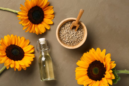 Sunflowers, bowl with seeds and bottle of oil on brown backgroundの写真素材