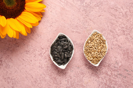 Sunflower and bowls with seeds on pink backgroundの写真素材