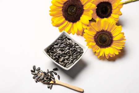 Sunflowers and bowl with seeds on white backgroundの写真素材