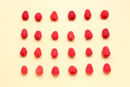 Many fresh raspberries on yellow background