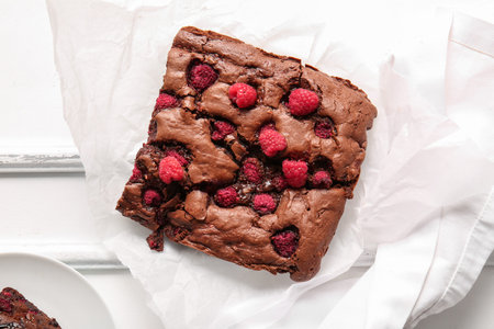 Baking paper with raspberry chocolate brownie on white background