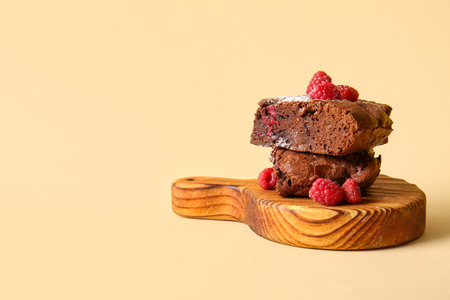 Wooden board with pieces of raspberry chocolate brownie on orange backgroundの写真素材