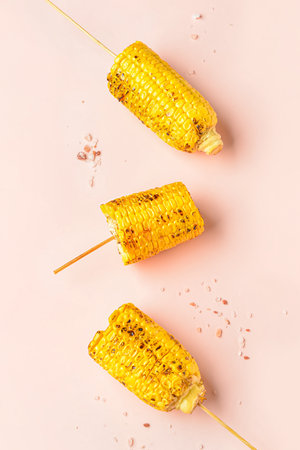 Tasty grilled corn cob skewers on pink backgroundの写真素材